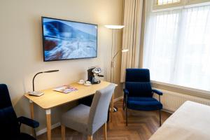 Habitación con mesa, 2 sillas y TV. en Hotel Van Walsum, en Róterdam