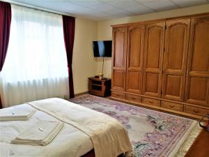 een slaapkamer met een bed, houten kasten en een raam bij Tudor Central House Sibiu in Sibiu