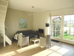 a living room with a couch and chairs at Luxe vakantiewoning Zeeduinsepoort met Sauna in Oostkapelle