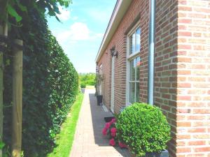 a brick building with a sidewalk next to a bush at Luxe vakantiewoning Zeeduinsepoort met Sauna in Oostkapelle