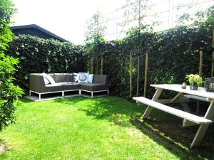 a garden with a couch and a table in the grass at Luxe vakantiewoning Zeeduinsepoort met Sauna in Oostkapelle