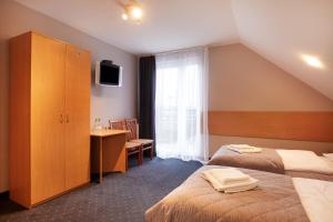 a hotel room with two beds and a desk and a window at Hotel Wena in Kielce