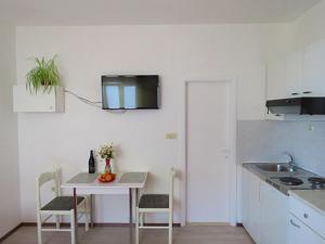 Il comprend une cuisine avec une table et une télévision murale. dans l'établissement Apartments Neda, à Omiš