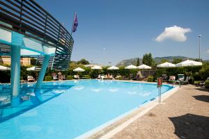 une grande piscine bleue avec des parasols dans un complexe dans l'établissement Hotel Poseidon, à Terracine