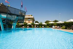 une grande piscine bleue avec des chaises et des parasols dans l'établissement Hotel Poseidon, à Terracine