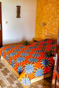 een slaapkamer met een bed met een oranje en blauwe deken bij Hotel Robinson Plage in Lomé