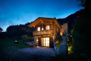 uma casa de madeira à noite com as luzes acesas em Auhäuslgut em Saalfelden am Steinernen Meer