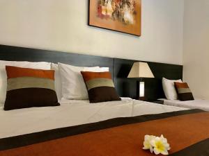 a bedroom with a large white bed with a black headboard at The Celuk Homestay in Jimbaran