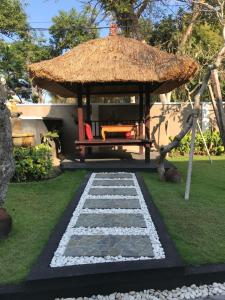 a gazebo with a bench and a grass at The Celuk Homestay in Jimbaran