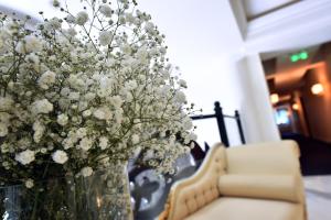 a vase filled with white flowers next to a couch at Hotel Ziya in Podgorica