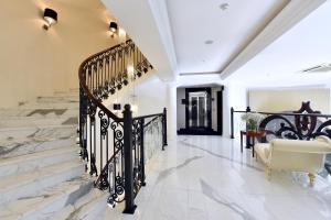 a hallway with white walls and a staircase with black railings at Hotel Ziya in Podgorica