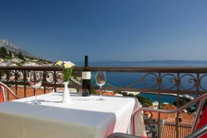 a table with wine glasses and flowers on a balcony at Villa King Apartments in Brela