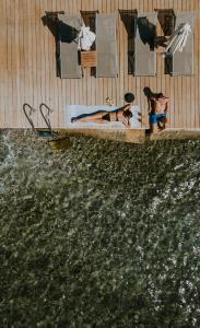 een paar mensen in een zwembad naast een lichaam water bij Pefkaki Boutique Hotel Loutraki in Loutraki