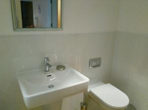 La salle de bains blanche est pourvue d'un lavabo et de toilettes. dans l'établissement South Fistral Seaview 2-bed Apartment, à Newquay