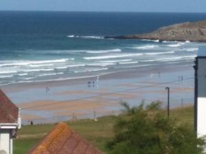 - une vue sur la plage avec des gens dans l'eau dans l'établissement South Fistral Seaview 2-bed Apartment, à Newquay