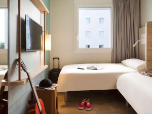 um quarto de hotel com duas camas e uma televisão em ibis budget Fribourg em Fribourg