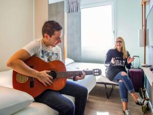 um homem a tocar guitarra ao lado de uma mulher em ibis budget Fribourg em Fribourg