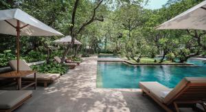 a pool with chairs and umbrellas next to a resort at The Dharmawangsa Jakarta in Jakarta