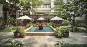 a swimming pool with tables and chairs and umbrellas at The Dharmawangsa Jakarta in Jakarta