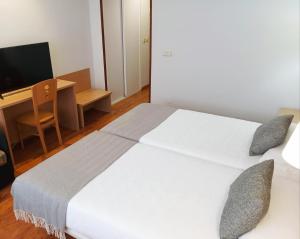 a bedroom with a large white bed and a desk at Hotel San Millán in Santander