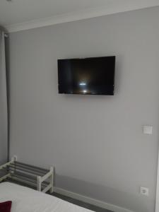 a flat screen tv on the wall of a bedroom at Casa da Leninha in Nazaré