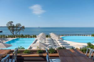 uma piscina com cadeiras brancas e o oceano em Maistra Camping Amarin Mobile homes em Rovinj