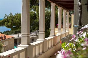 a balcony with columns and flowers on a building at Villa King Apartments in Brela