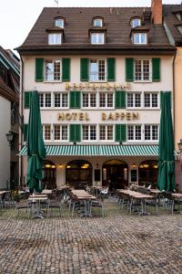 un hôtel avec des tables et des parasols devant lui dans l'établissement Hotel Rappen am Münsterplatz, à Fribourg-en-Brisgau