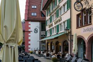 un café en plein air avec des tables et des chaises et une horloge dans un bâtiment dans l'établissement Hotel Rappen am Münsterplatz, à Fribourg-en-Brisgau