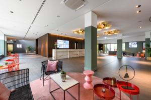 un hall avec des tables et des chaises dans un bâtiment dans l'établissement Mercure Hotel Wiesbaden City, à Wiesbaden