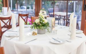 ein weißer Tisch mit weißen Platten und Blumen darauf in der Unterkunft Hotel Grasberger Hof GmbH in Grasberg