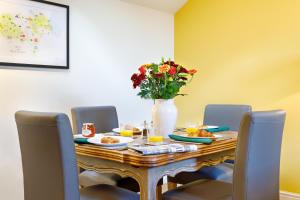 a dining room table with a vase of flowers on it at The Old Sweet Factory in Harrogate