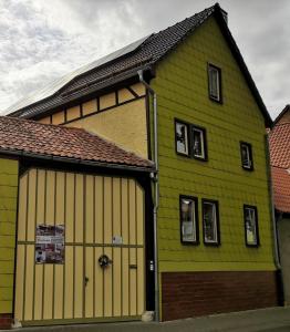 ein großes grünes und gelbes Gebäude mit einer Garage in der Unterkunft Ferienwohnung Auf dem Hofe in Bad Langensalza