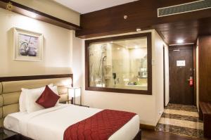 a hotel room with a bed and a mirror at KPM TRIPENTA HOTEL in Kozhikode