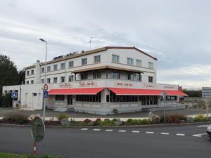 een wit gebouw met een rode luifel op een straat bij Hôtel Le Sully La Roche Sur Yon in La Roche-sur-Yon