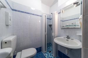 y baño con aseo blanco y lavamanos. en Hotel Vina De Mar, en Lignano Sabbiadoro