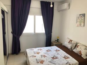 1 dormitorio con 1 cama y una ventana con cortinas azules en Tetris Apartment Spacious Comfortable, en Lefkosa Turk