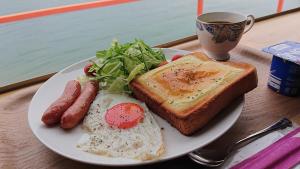 un piatto di prodotti per la colazione con uova tostato e una tazza di caffè di Sea Side Hostel Light House a Onomichi