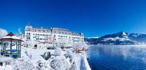 um edifício com um gazebo na neve ao lado de um lago em Grand Hotel Zell am See em Zell am See