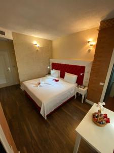 a bedroom with a large bed with a red headboard at The Red Bricks Hotel in Shkodër