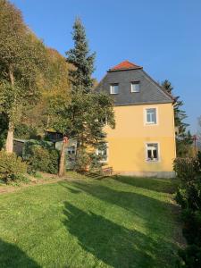 une maison jaune avec un banc dans une cour dans l'établissement Ferienhaus Elbufer 83, à Bad Schandau