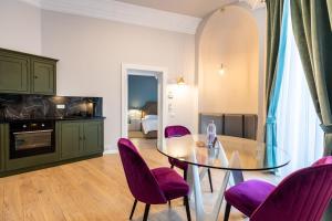 une salle à manger avec une table en verre et des chaises violettes dans l'établissement Matisse Bucharest Old Town, à Bucarest