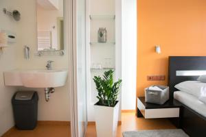 a bathroom with a sink next to a bed at Hotel Krystal in Luhačovice