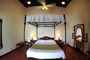 1 dormitorio con cama con dosel y ventilador de techo en Lake Palace, en Thekkady