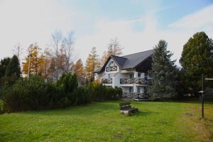 ein weißes Haus mit schwarzem Dach auf einem grünen Hof in der Unterkunft Vila Horec - depandance hotela Hubert Vital Resort in Vysoké Tatry