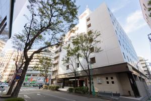 ein hohes weißes Gebäude in einer Stadtstraße in der Unterkunft Toyo Hotel in Fukuoka