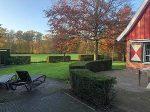 a patio with two chairs next to a brick building at De Lindenburg met privé hottub, sunshower, sauna, grote tuin met weidezicht en vrije ligging, 6-persoons in Lievelde