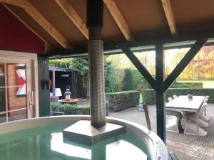 an outdoor patio with a table and a pillar at De Lindenburg met privé hottub, sunshower, sauna, grote tuin met weidezicht en vrije ligging, 6-persoons in Lievelde