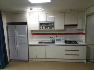 a kitchen with white cabinets and a sink and a microwave at Hotel Joy near Camp Humphres in Pyeongtaek