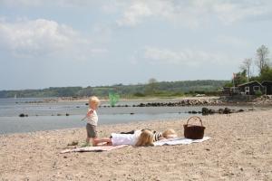 Due bambini sdraiati su una spiaggia con un bambino di Loff Holiday Houses a Aabenraa